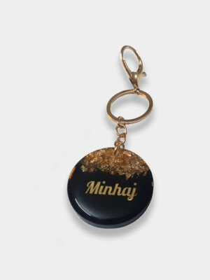 Personalized black resin keychain with gold foil flakes and custom name Minhaj in gold lettering